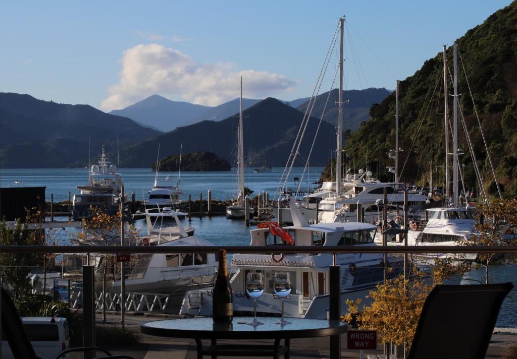 a marina with boats and a table with wine glasses at The Moorings - Luxury Waterfront Apartment in Picton