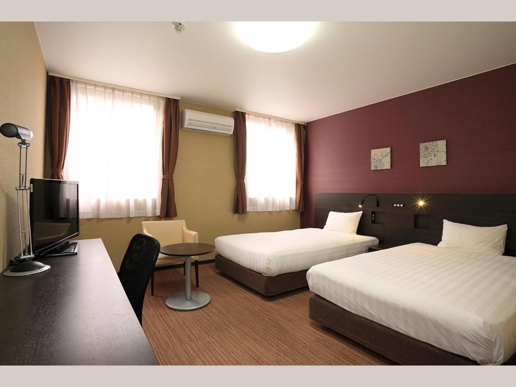 a hotel room with two beds and a television at Smile Hotel Otsu Seta in Otsu