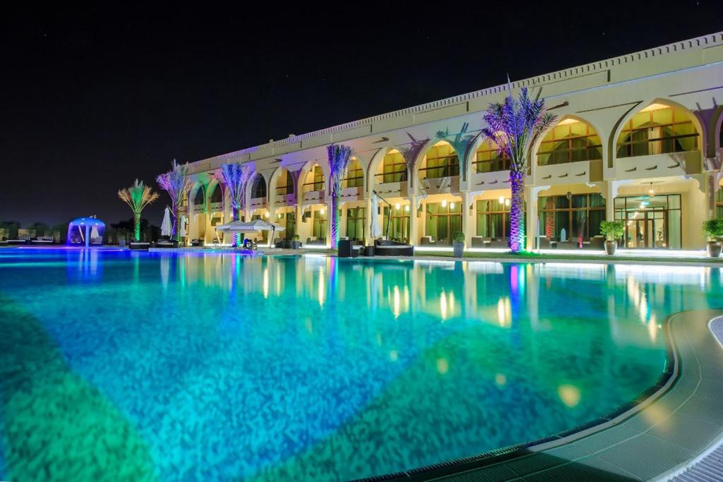 a large swimming pool in front of a building at night at Western Hotel - Madinat Zayed in Madīnat Zāyid