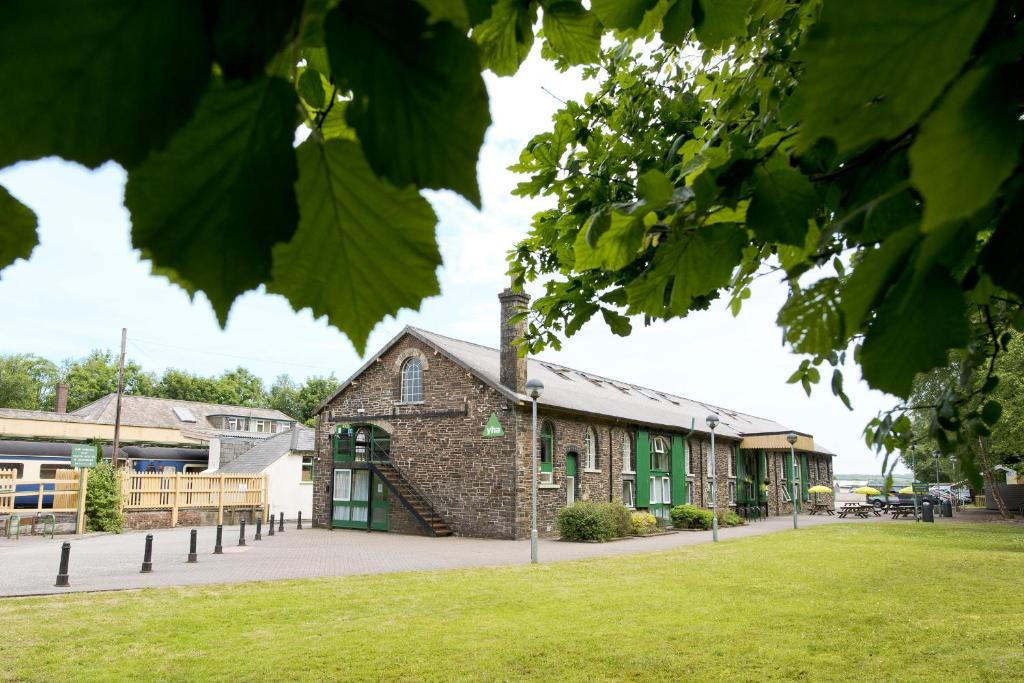 un edificio de ladrillo con puertas verdes y un campo de césped en YHA Okehampton, en Okehampton