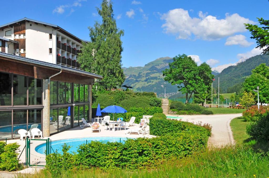 un complexe avec une piscine et des montagnes en arrière-plan dans l'établissement AEC Vacances - Forgeassoud, à Saint-Jean-de-Sixt