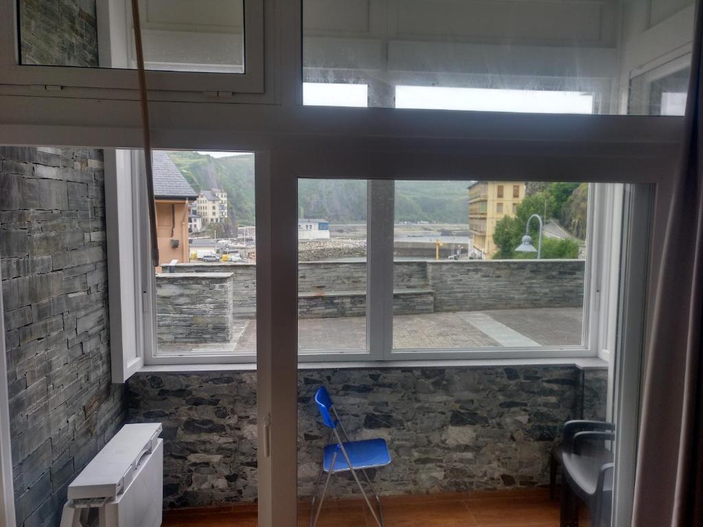 a window with a blue chair in a room with a view at Apartamentos turísticos Vistademar in Luarca