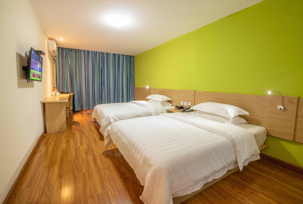 two beds in a hotel room with green walls at Orange Fashion Apartment Hotel Guangzhou Xiajiao Subway Station Branch in Guangzhou