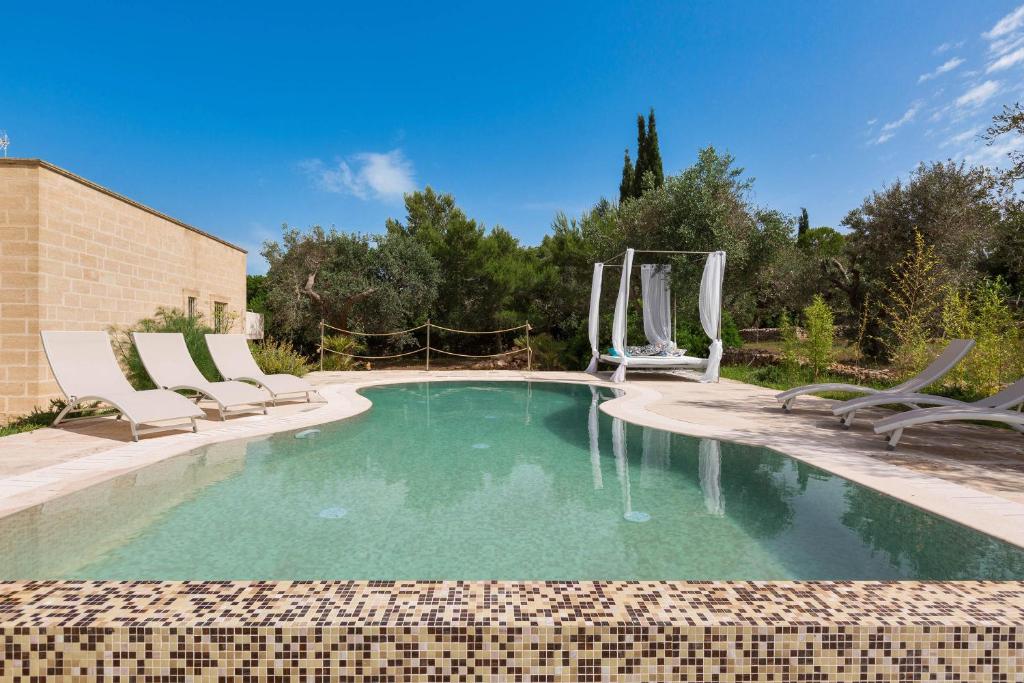 une piscine avec deux chaises et une piscine dans l'établissement Villa Satis by Perle di Puglia, à Casarano