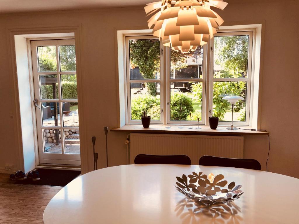a dining room with a table and two windows at Østre Alle 38 in Hjørring