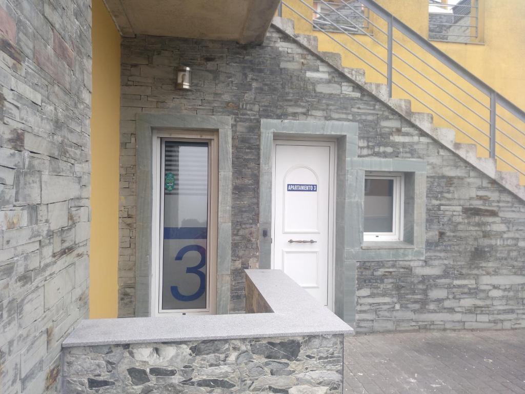 a building with a white door with a number three at Apartamentos turísticos Vistademar in Luarca