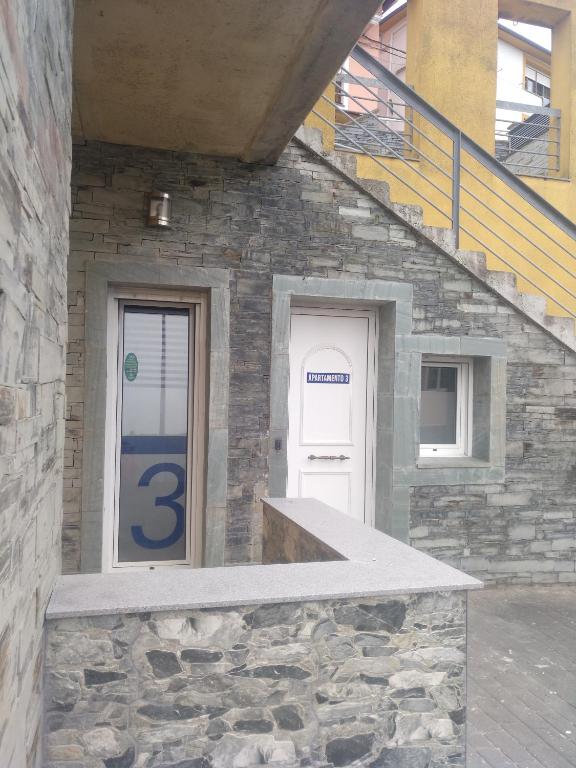 a stone building with a white door and a staircase at Apartamentos turísticos Vistademar in Luarca