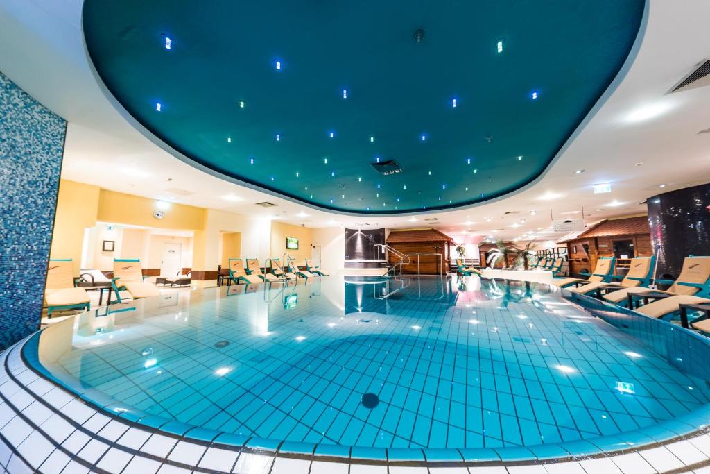 ein großer Pool in einem Hotel mit blauer Decke in der Unterkunft Mauritius Hotel & Therme in Köln