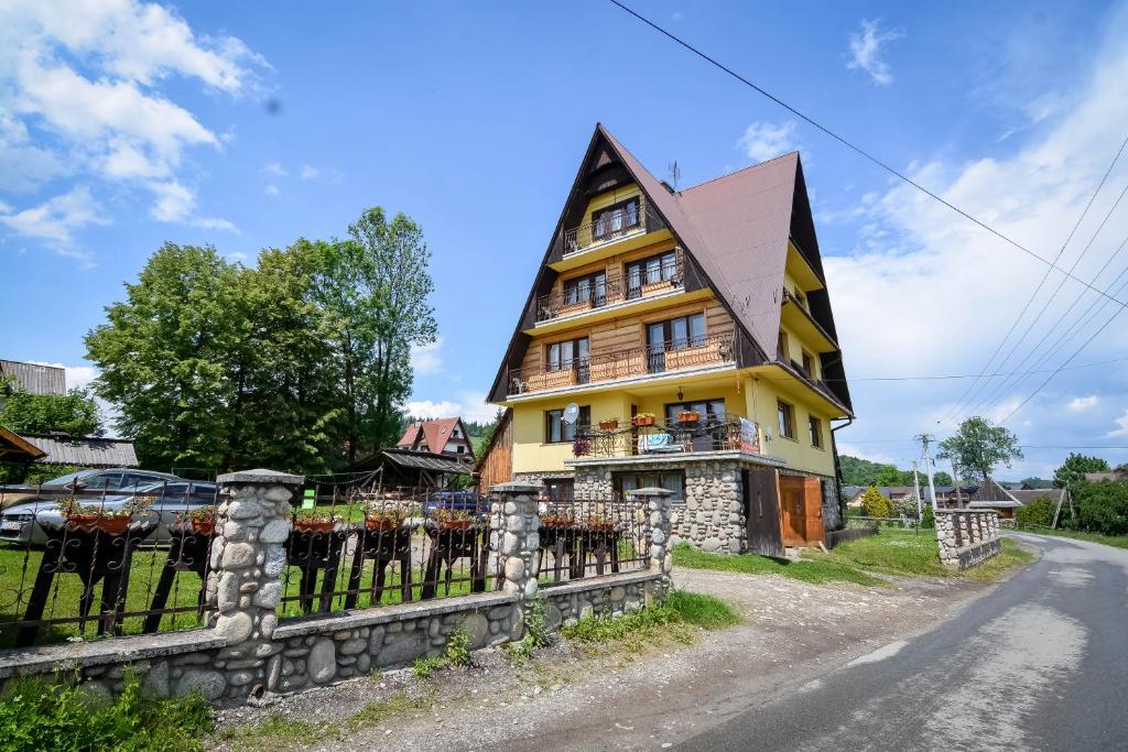 żółty dom z płotem przy drodze w obiekcie Dom Wypoczynkowy u Ewy w Białym Dunajcu