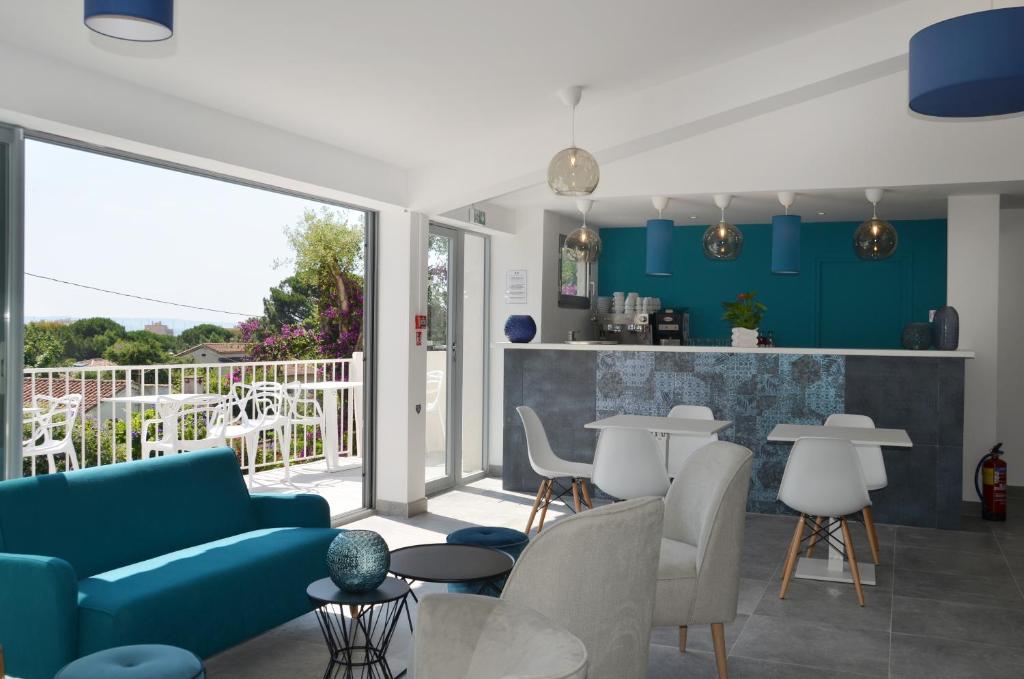 a living room with a blue couch and chairs at Hotel La Voile in Bormes-les-Mimosas