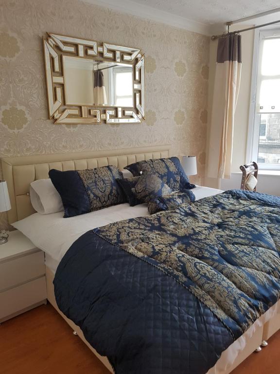 a bedroom with a large bed and a mirror at Loch Lomond Apartments in Dumbarton