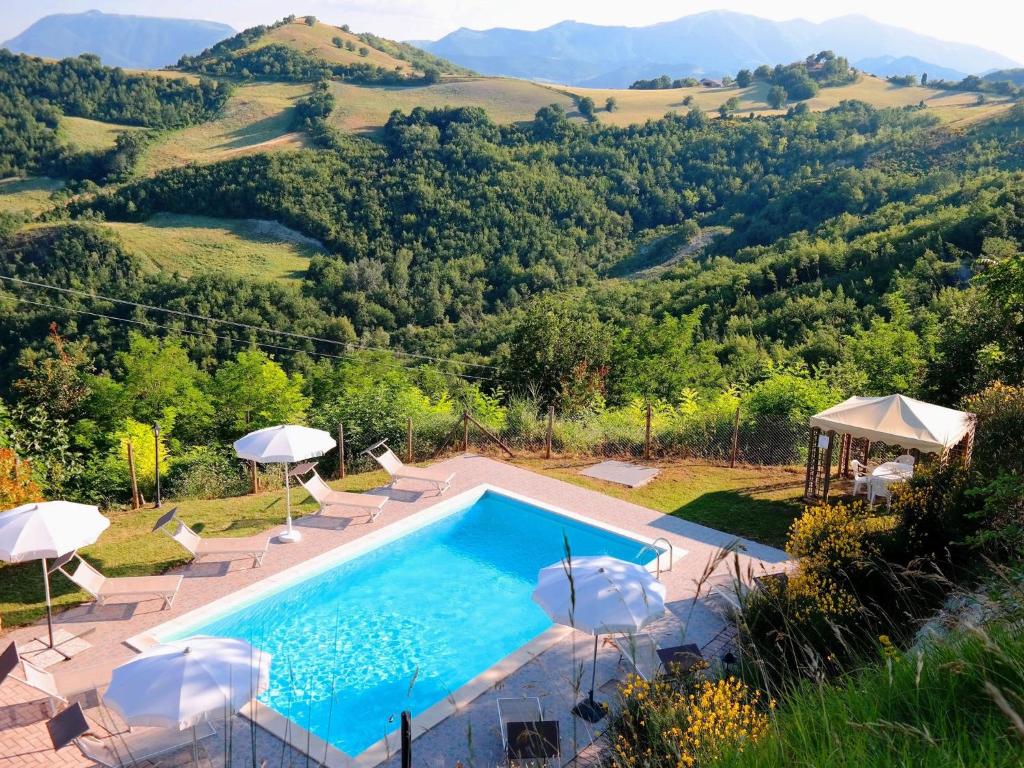 a swimming pool with chairs and umbrellas and a mountain at Belvilla by OYO Giulio in Acqualagna