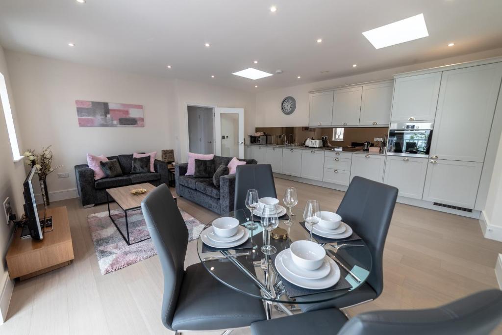 a kitchen and living room with a glass table and chairs at Reading Green Park Village Serviced Apartments in Reading
