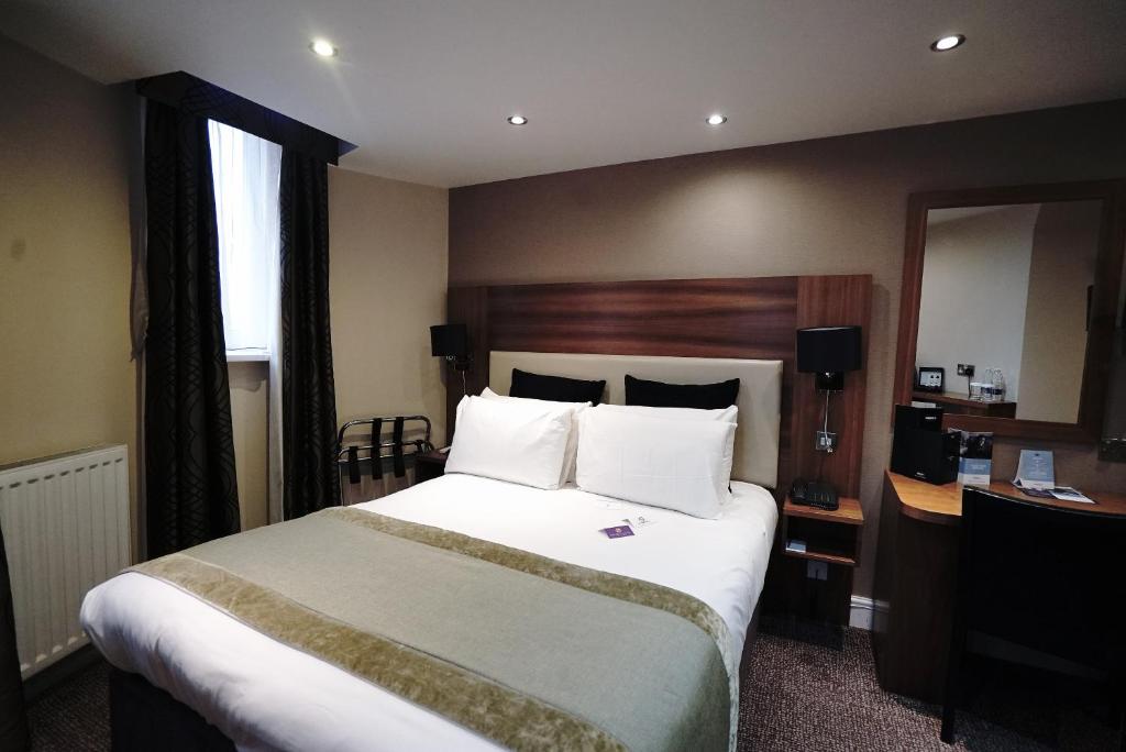 een hotelkamer met een groot bed en een spiegel bij Mercure London Bloomsbury Hotel in Londen