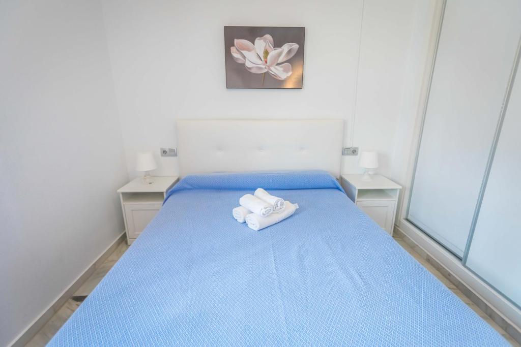 a bedroom with a blue bed with towels on it at Apartamentos Las Rosas de Capistrano in Nerja