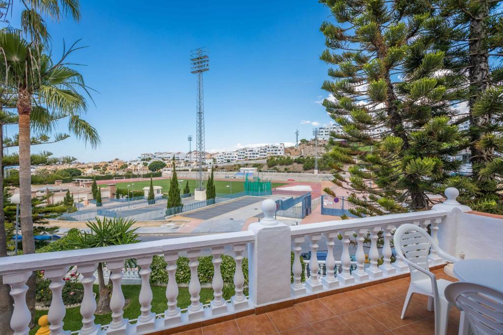 a balcony with a white railing and palm trees at Apartamentos Las Rosas de Capistrano in Nerja