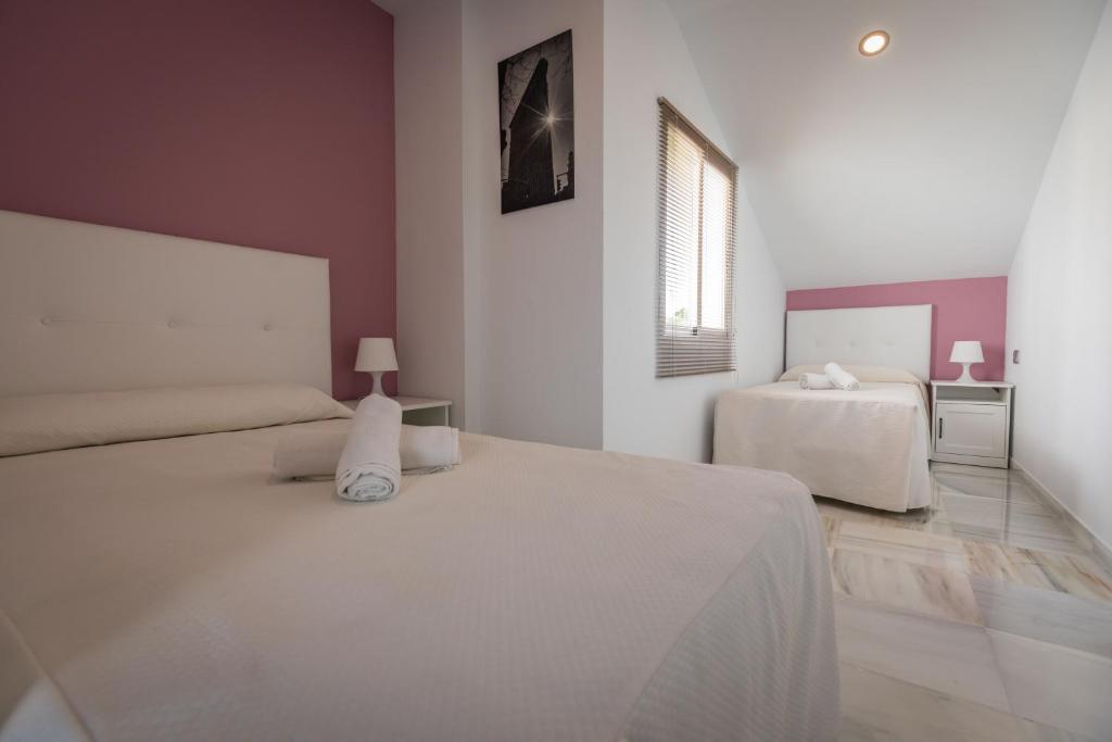 a white bedroom with two beds and a window at Apartamentos Las Rosas de Capistrano in Nerja