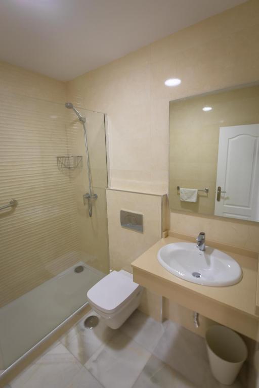 a bathroom with a sink and a toilet and a mirror at Apartamentos Las Rosas de Capistrano in Nerja