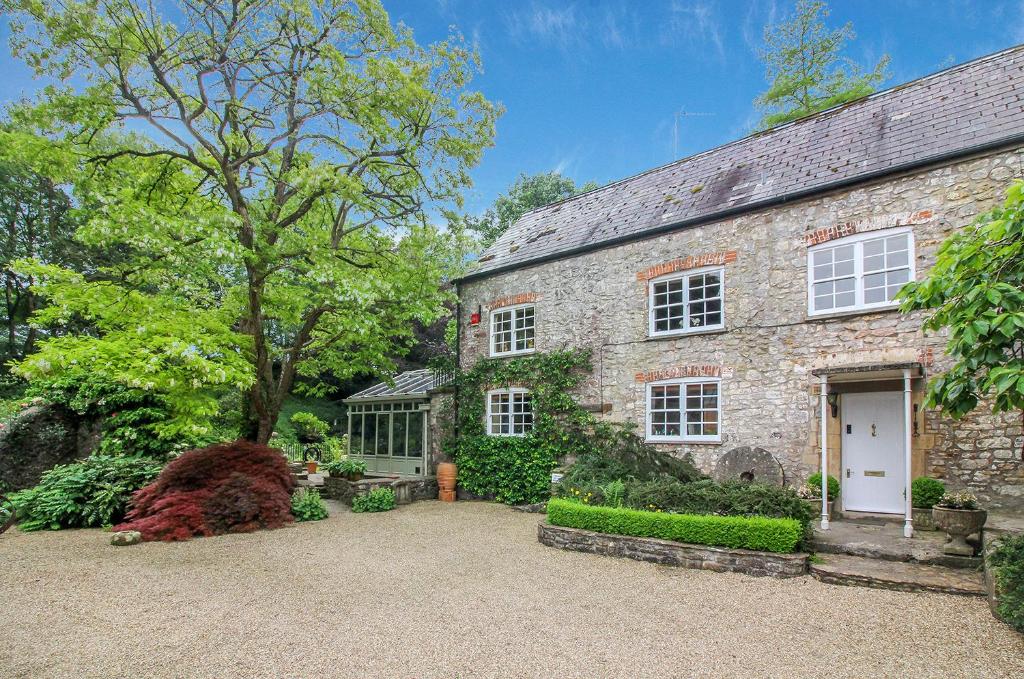 una antigua casa de piedra con un jardín delante de ella en Stay at Penny's Mill, en Frome