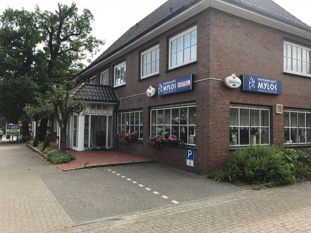 a brick building with a parking lot in front of it at Hotel Mylos in Sittensen