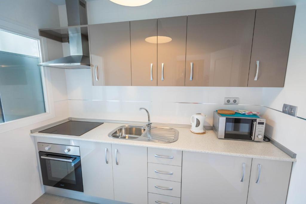 a kitchen with a sink and a microwave at Apartamentos Las Rosas de Capistrano in Nerja