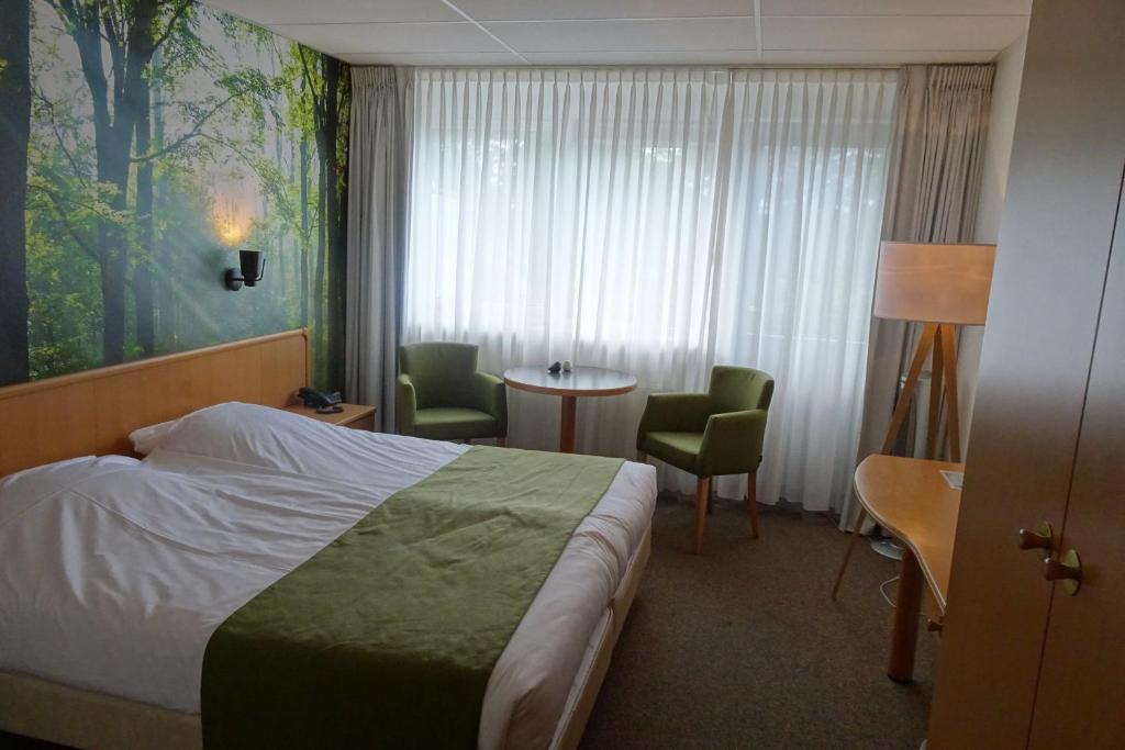 um quarto de hotel com uma cama, uma mesa e cadeiras em HCR Prinsen em Haarlo