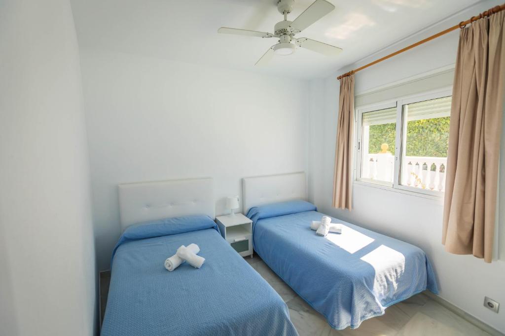 a bedroom with two beds and a window at Apartamentos Las Rosas de Capistrano in Nerja