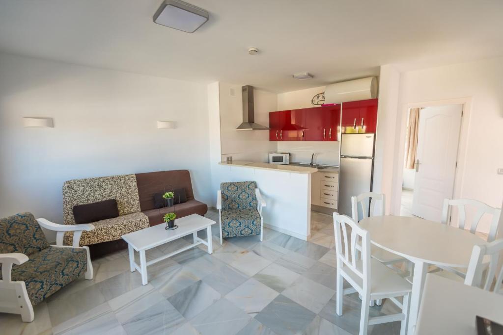 a kitchen and a living room with a table and chairs at Apartamentos Las Rosas de Capistrano in Nerja