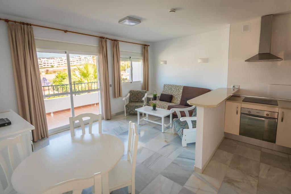 a kitchen and living room with a table and chairs at Apartamentos Las Rosas de Capistrano in Nerja