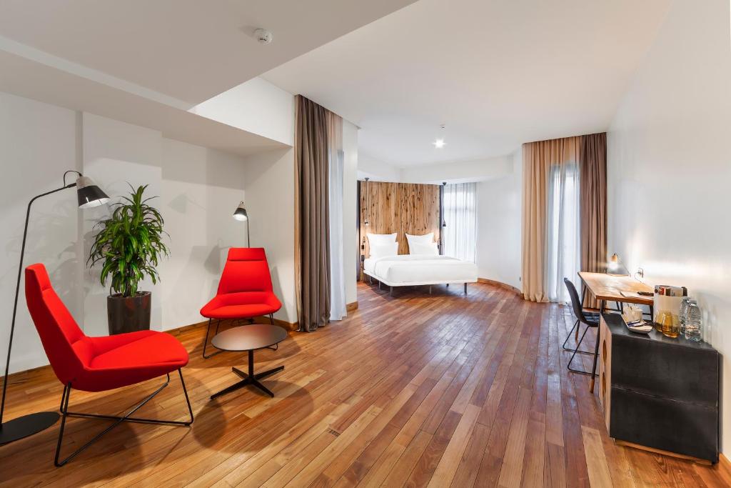 a living room with red chairs and a bed at Shota @ Rustaveli Boutique Hotel in Tbilisi City