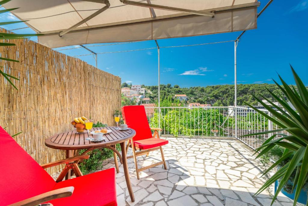 a patio with red chairs and a table with a view at Cozy new flat for 2 or 3 in Hvar