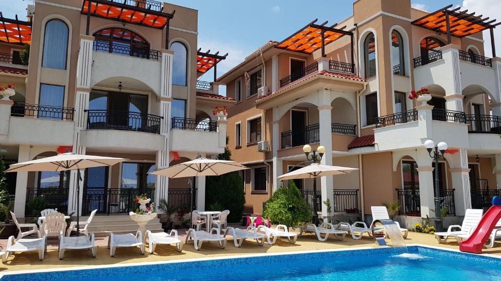 a hotel with a swimming pool and chairs and umbrellas at Brilliant Aparthotel in Sozopol