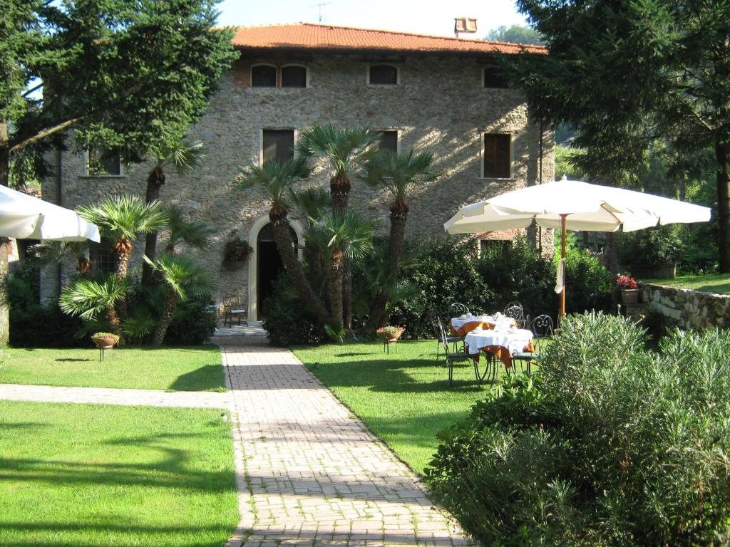 a garden with tables and umbrellas in front of a building at L'Arcadia in Pietrasanta
