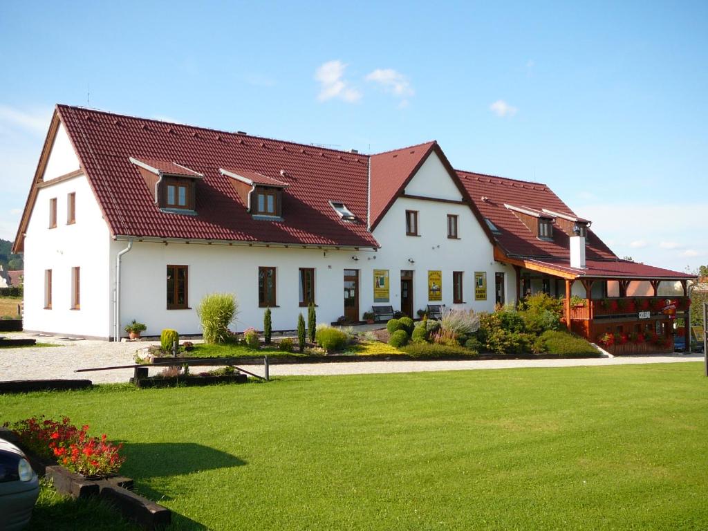 une grande maison blanche avec un toit rouge dans l'établissement Penzion Praktik Krumlov, à Přísečná