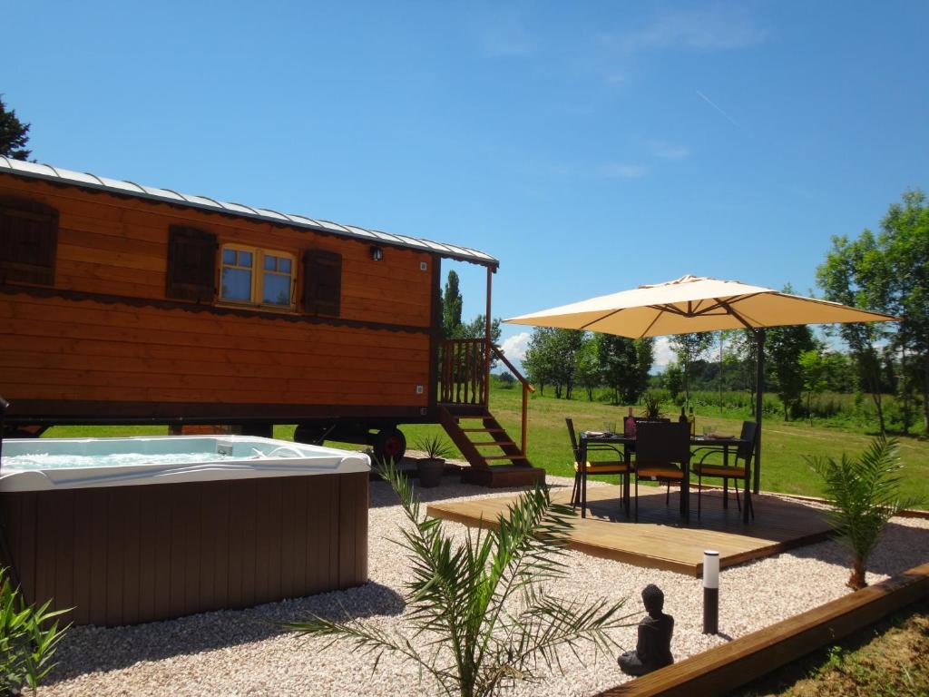 une maison avec un bain à remous et un parasol dans l'établissement L'Oasis Des Pyrénées, à Campuzan
