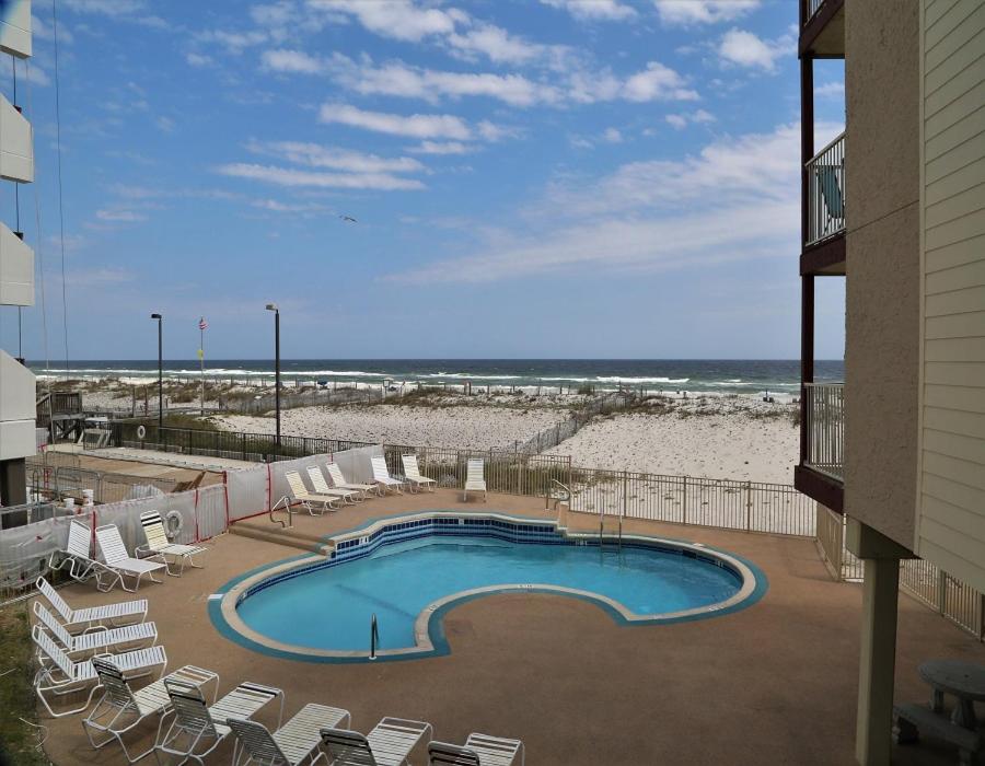 einen Pool mit Stühlen und Strand in der Unterkunft Southern Sands 104 Condo in Gulf Shores