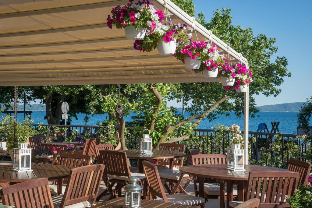 特雷維那諾羅馬諾的住宿－Malì Trevignano Piccolo Hotel，庭院设有木桌、椅子和鲜花