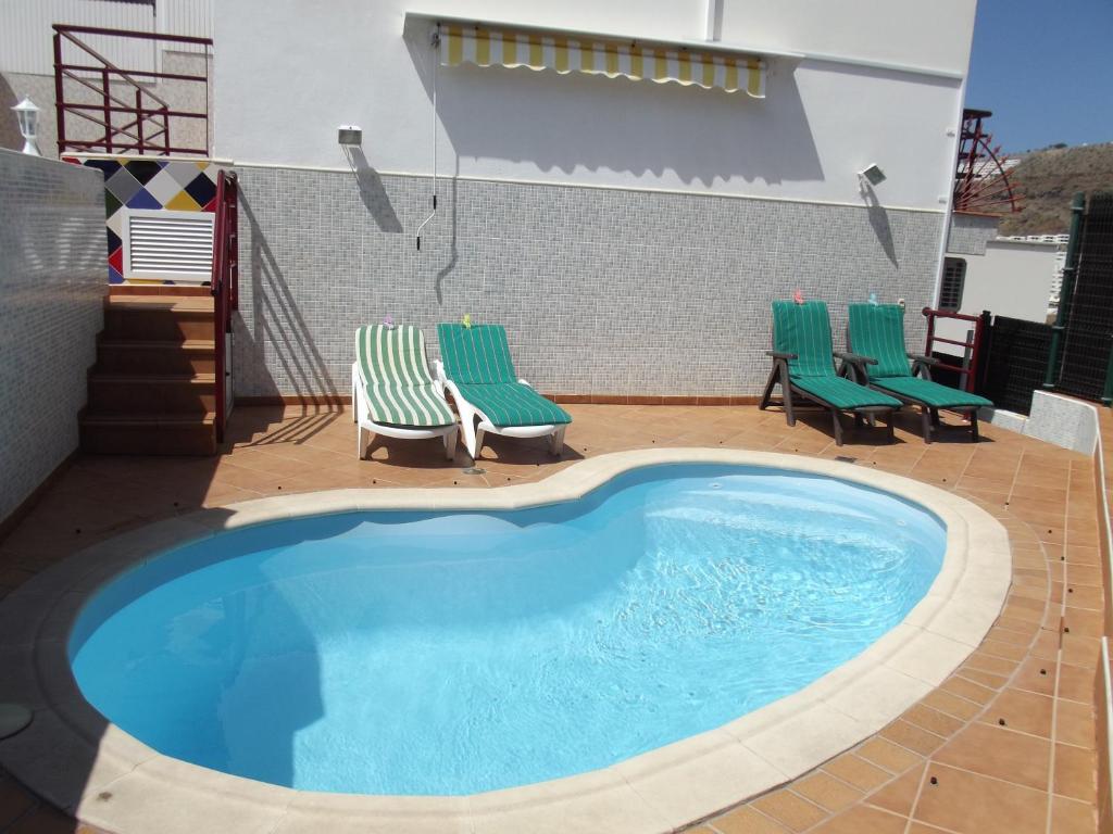 una piscina con 2 sillas de jardín y un par de sillas en Lancelot, en Puerto Rico de Gran Canaria