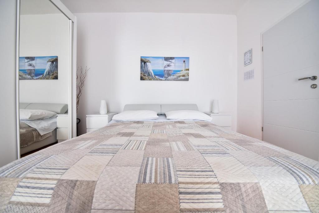 Un dormitorio blanco con una cama y un espejo. en Villa Benelux, en Zadar