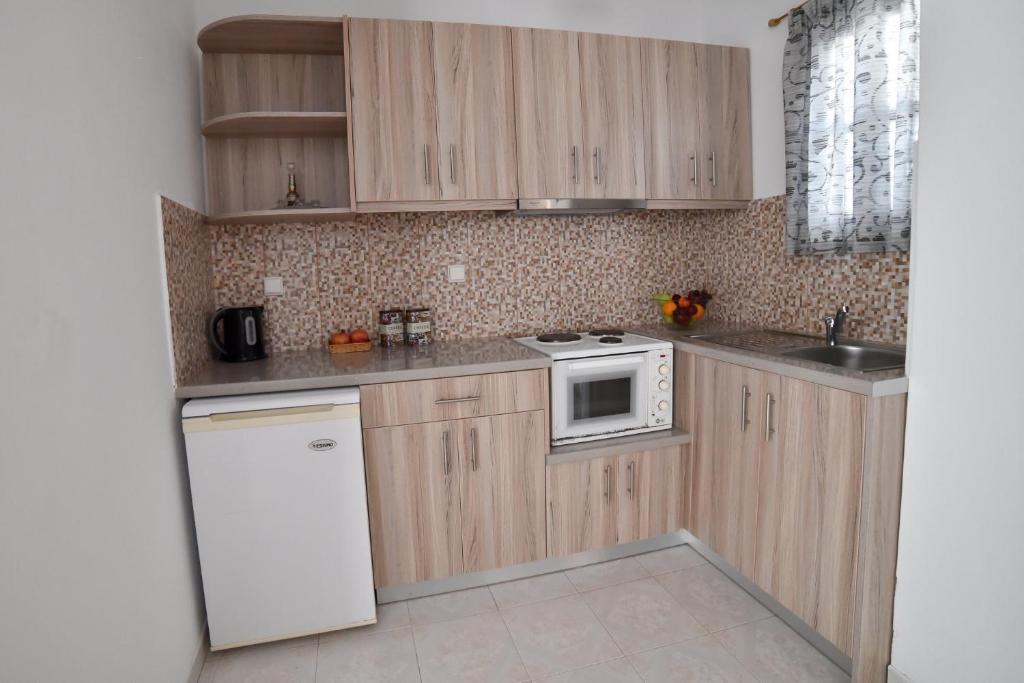 eine Küche mit Holzschränken und einer weißen Mikrowelle in der Unterkunft Pension Galini in Katápola