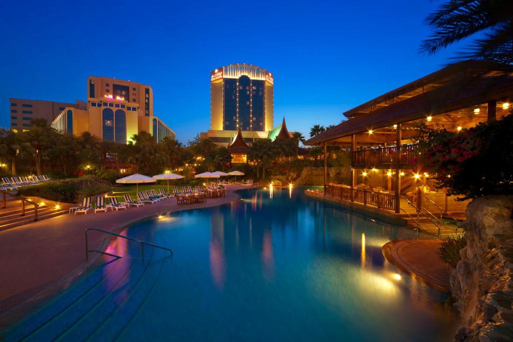 Gulf Hotel Bahrain في المنامة: مسبح كبير في المدينة ليلا