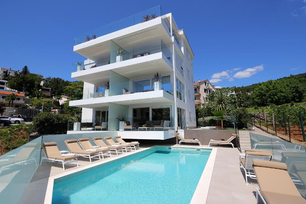a building with a swimming pool and chairs and a building at Stylish apartment 100 m from the beach in Opatija