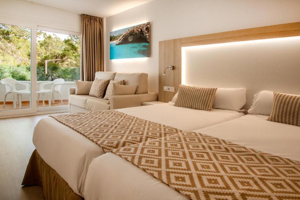 サンタ・ポンサにあるGlobales Costa de la Calmaのベッド2台とソファが備わるホテルルームです。