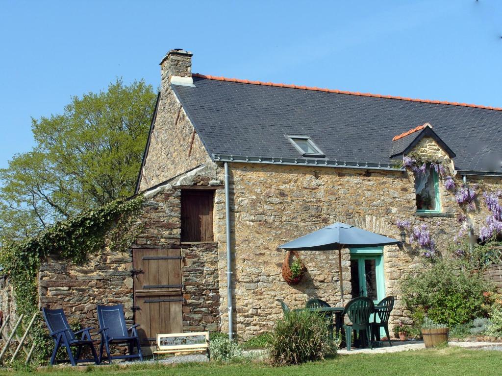 an old stone cottage with chairs and an umbrella at lesChenes in Saint-Dolay