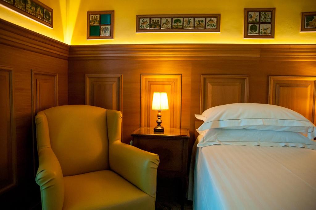 a bedroom with a bed and a chair and a lamp at Hotel Palladio in Giardini Naxos