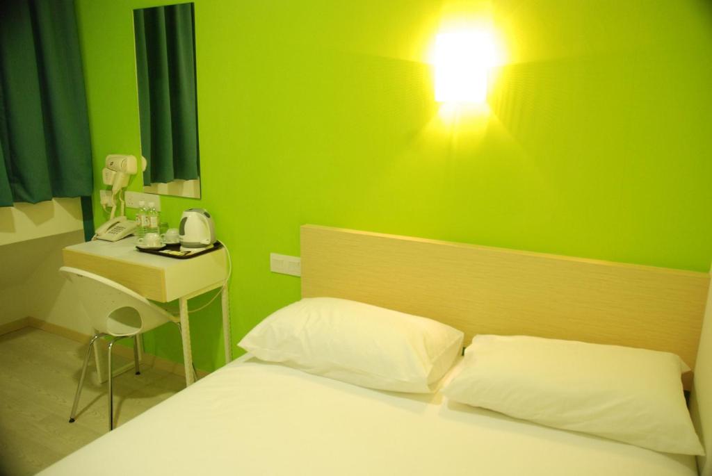 1 dormitorio con una pared verde, 1 cama y 1 lámpara en Old Penang Hotel - Penang Times Square, en George Town