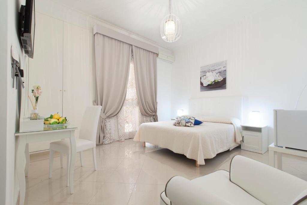 um quarto branco com uma cama, uma mesa e uma janela em San Nicola B&B em Castellammare di Stabia