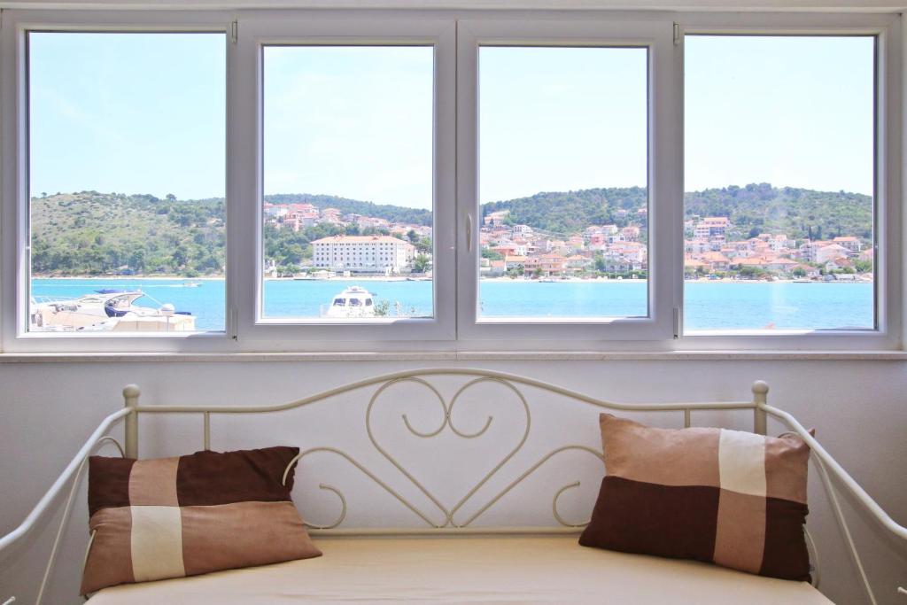 a bed in a room with three windows at Villa Merica in Trogir