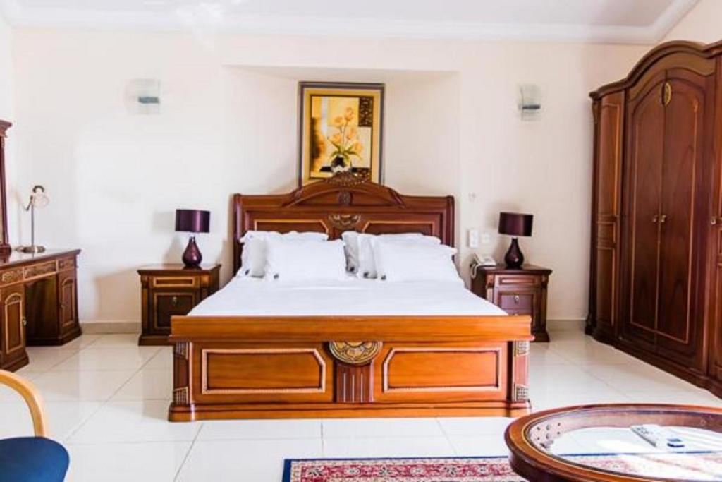 a bedroom with a large wooden bed and wooden furniture at Hotel Barmoi in Freetown