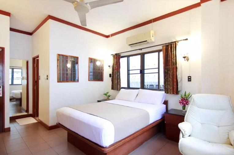 Buakao Inn في تونغسالا: غرفة نوم بسرير ابيض وكرسي